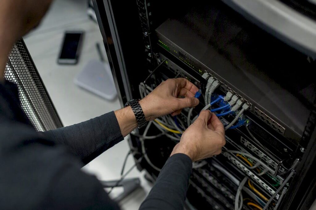 Hands unplugging network cable in server room