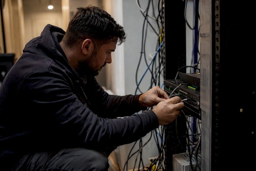 Hands unplugging network cable in server closet