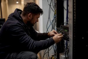 Hands unplugging network cable in server closet